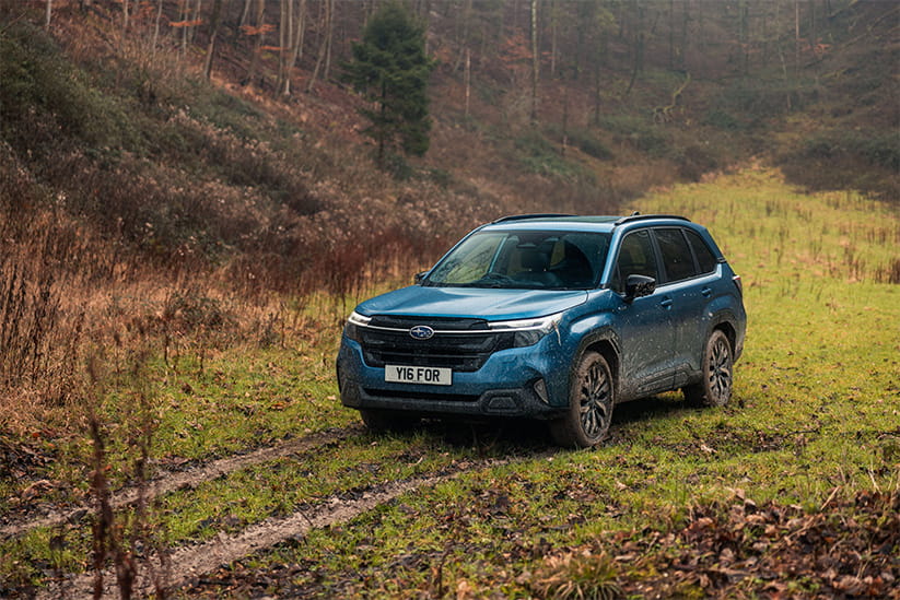 A blue Subaru Forester spattered with mud doing some light off-roading