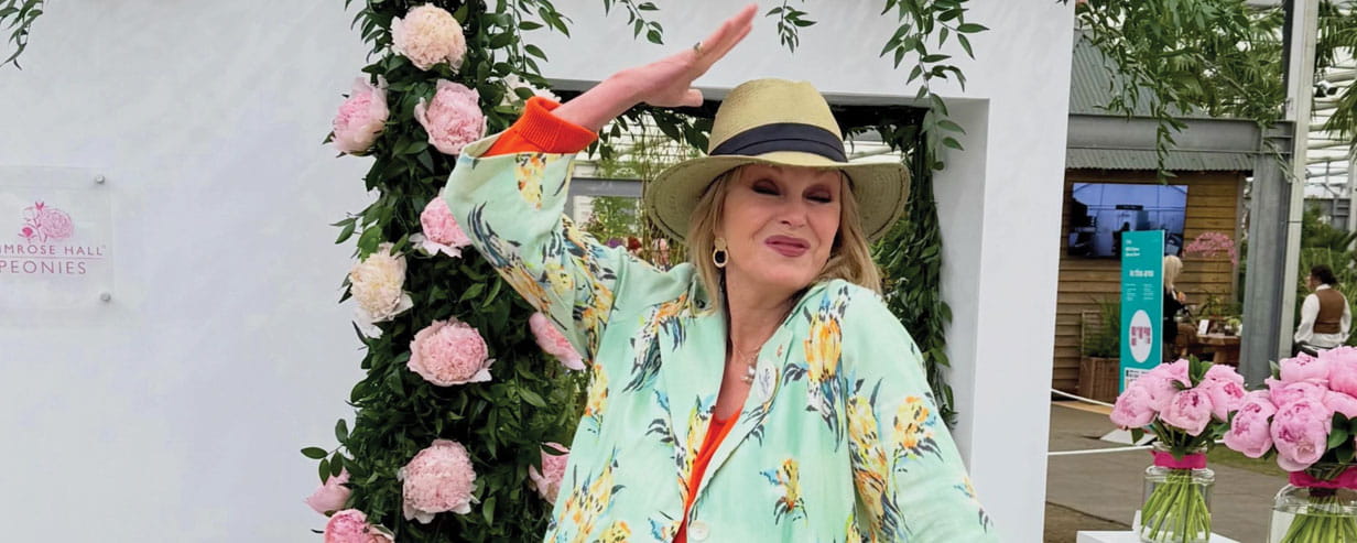 Joanna Lumley wearing a straw hat with peonies in the background at Chelsea 2026