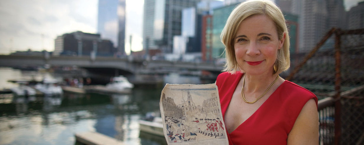 Lucy Worsley with part of the Boston skyline behind her showing an archival picture of the American Revolution