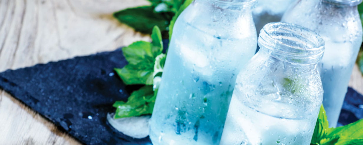 Very cold mineral water with ice in a misted glass bottles, dark background