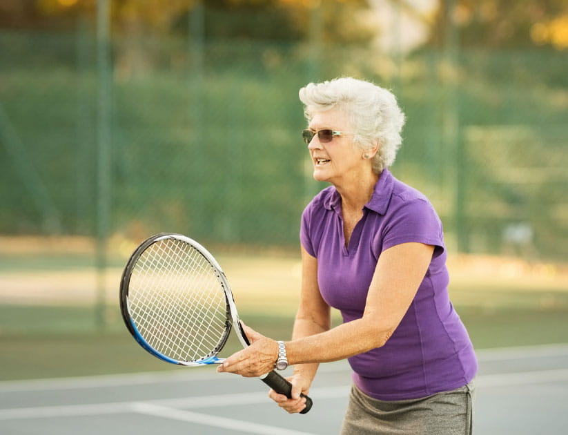 Mature woman playing tennis on court showing focus and concentration 