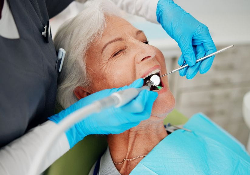 An older woman has her teeth checked at the dentist