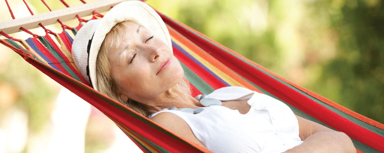 Mature woman relaxing in hammock wearing hat sleeping