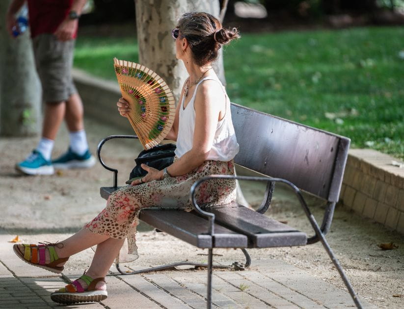 How to stay safe in a heatwave: a woman fanning herself 