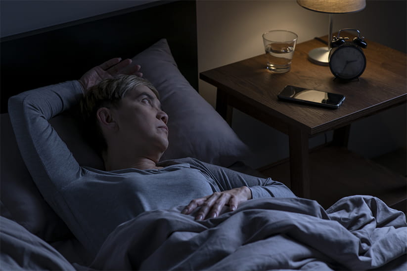 Senior woman lying in bed cannot sleep from insomnia