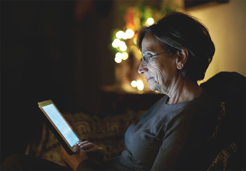 Senior woman reading on tablet at night 