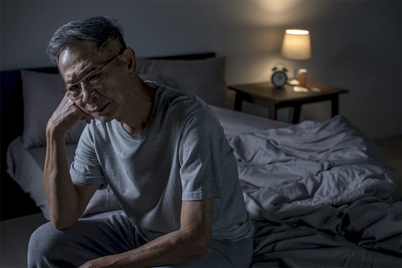 Senior Asian man sitting in bed cannot sleep from insomnia