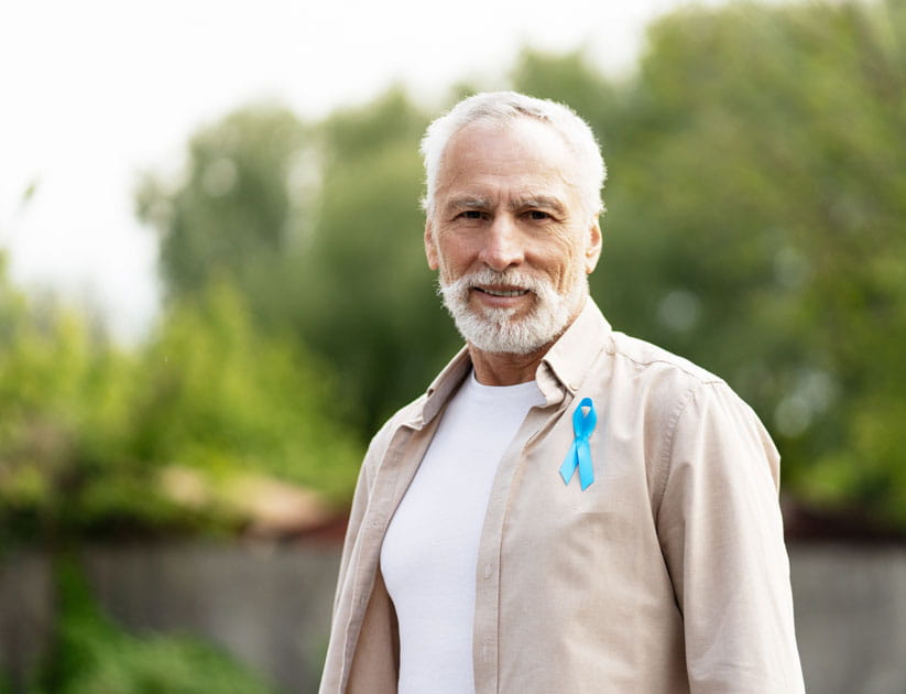 Senior man wearing light blue awareness ribbon supporting prostate cancer awareness month