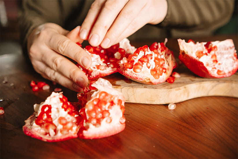 Woman eating pomegranate while sitting at the table