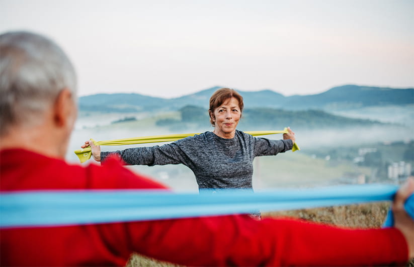 Senior couple exercising in nature, using resistance band