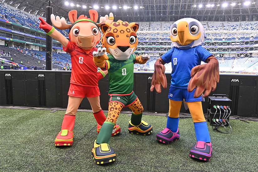 The three World Cup mascots on a pitch