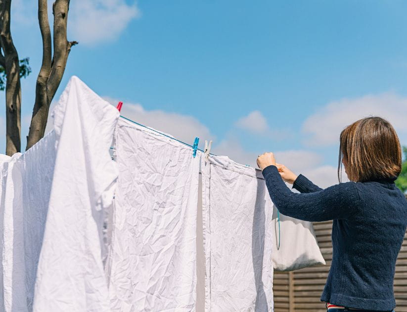A woman hanging white sheets on the clothes line