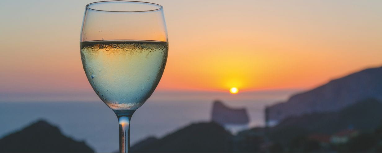 Glass of white wine with a sunset in the background
