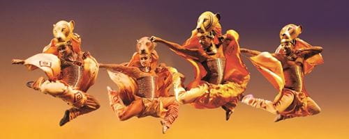 4 actors posed in the air, dressed in lion themed outfits for the Lion King musical