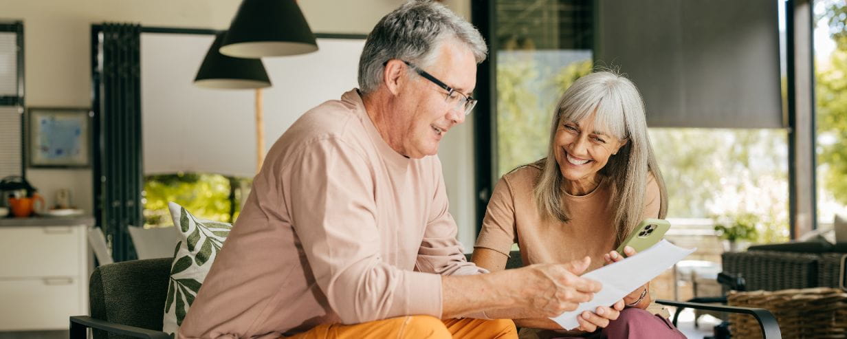 Mature man and woman looking at piece of paper smiling