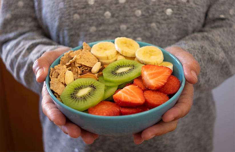 Close-up of female's hand holding a bowl of fresh and dried fruits