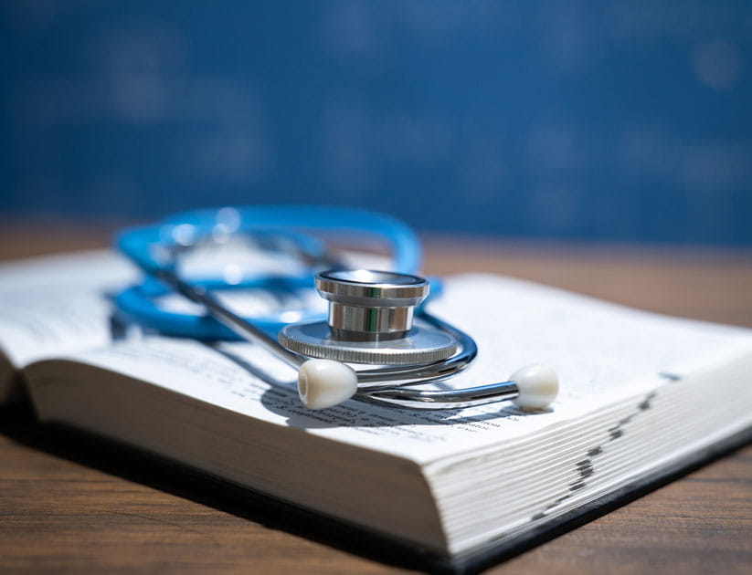 Medical textbook and stethoscope on desk