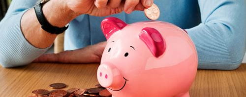 A woman puts pennies into a pink piggy bank