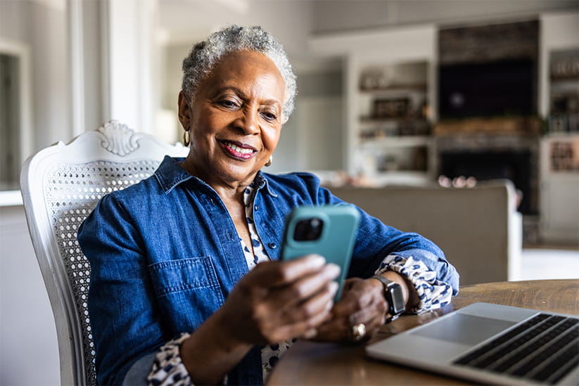  Senior woman using smartphone at kitchen table
