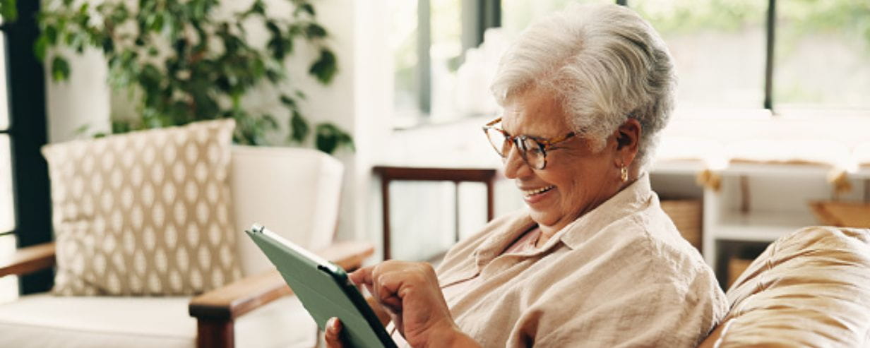 Woman on a sofa solving a puzzle on a tablet