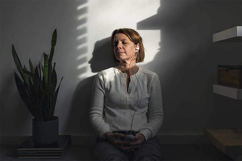 A mature woman uses a vagus nerve stimulation device in the last sun rays coming into the room