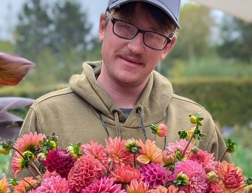 A portrait of a man holding a bunch of dahlias