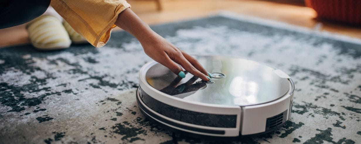 A hand guiding a robotic vaccum cleaner