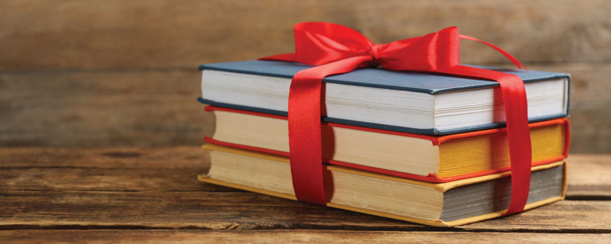 Different books tied with red ribbon on wooden table
