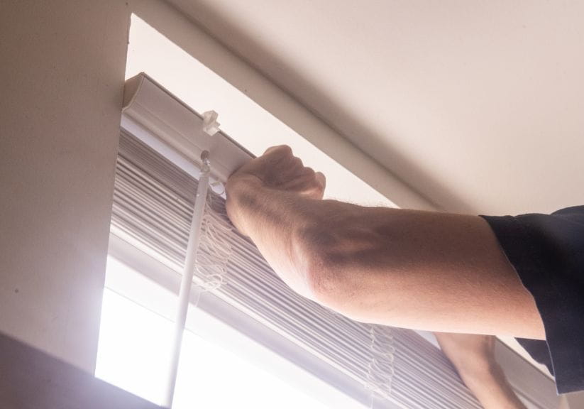 A close up of hands of a man putting a blind up