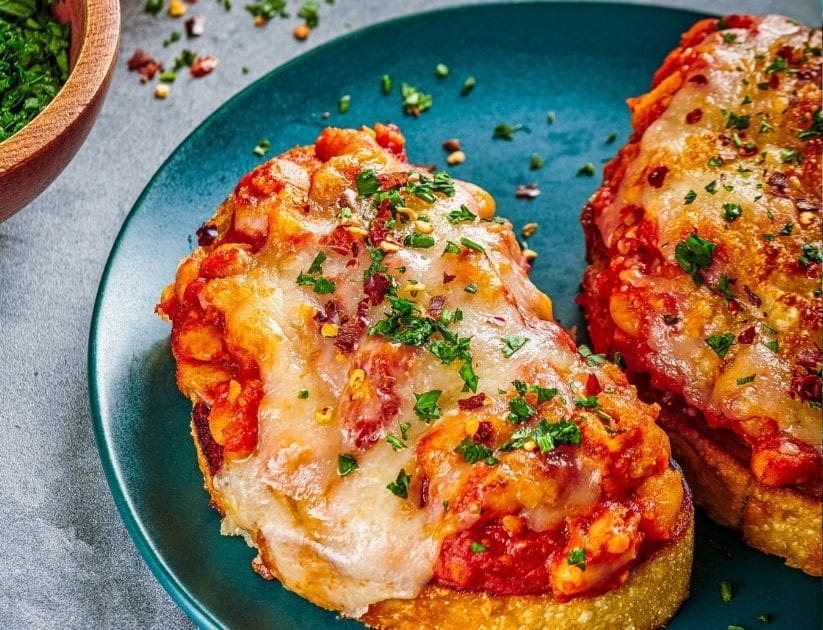 Two slices of toasted bread with beans on top and some cheese