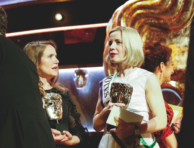 Two women hold their awards at an award show