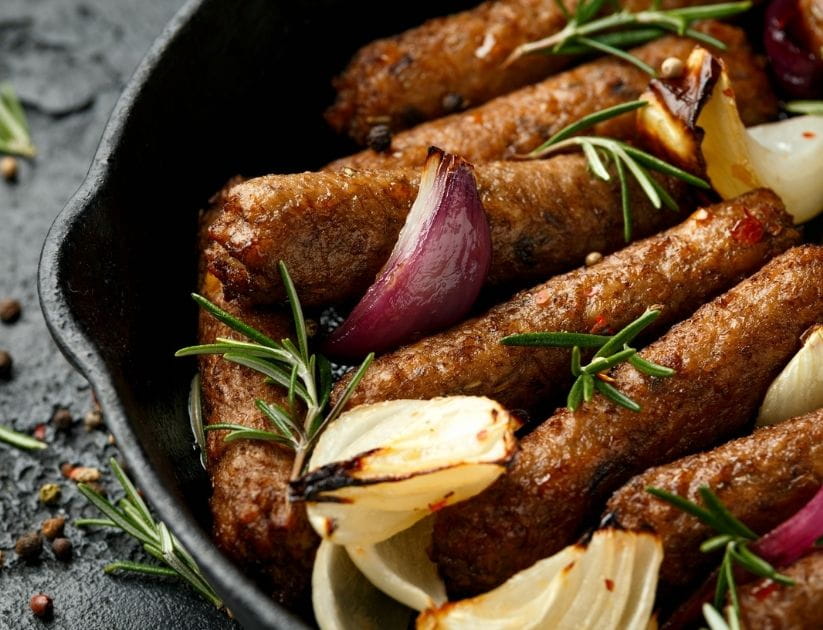 A Rosemary and onion vegetarian vegan sausages oven baked in cast iron skillet frying pan