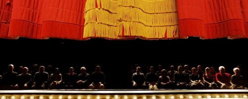 Red curtain descending on stage with the audience in background
