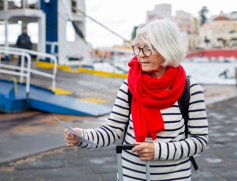 A lady at at the harbour, holding her ferry ticket as she travels by herself