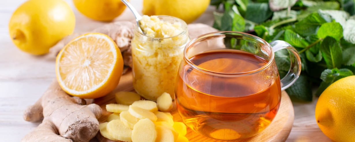 A spread of foods to help fight a cold, including ginger, lemon and green leaf veg