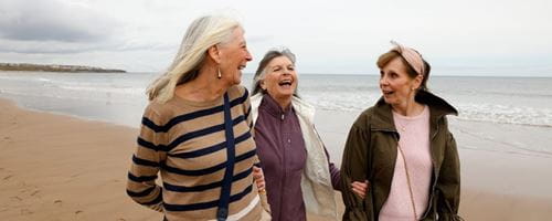 Three friends walking along an empty beach enjoying time together