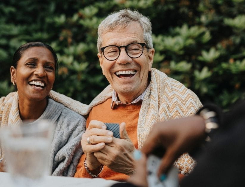 Cheerful man playing cards with family members at a garden party