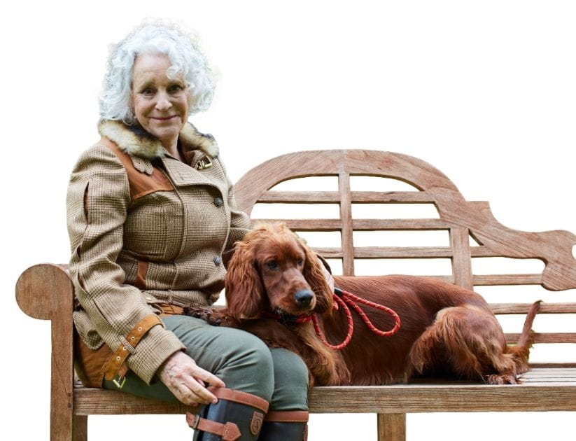 A woman sits on a wooden bench with a dog