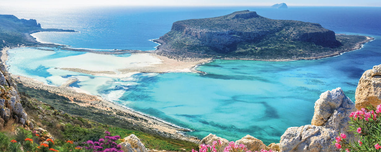 Balos Beach, located on the northwestern tip of Crete near Kissamos, is famous for its striking lagoon of turquoise waters, soft white and pink-tinged sand, and dramatic surrounding cliffs