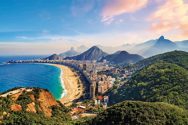 A scenic shot of a beach in Brazil with mountains in the distance