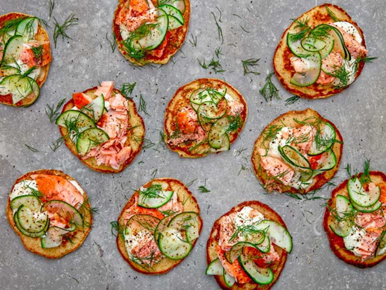 Top-down view of salmon blinis with garnish