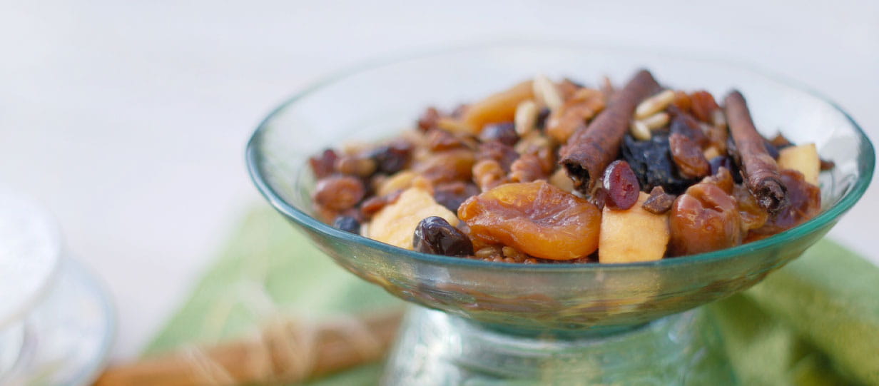 Fruit compote, with raisins, dried plums, apple, pine seeds, cinnamon, dried apricot, dates in a glass bowl