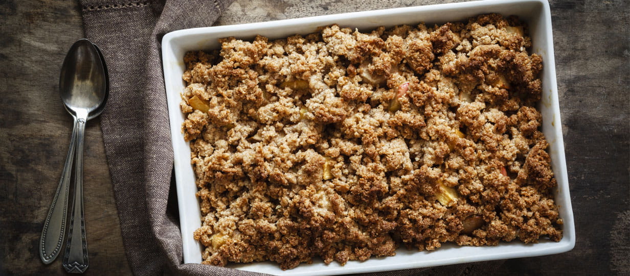 A white ceramic dish filled with apple crumble