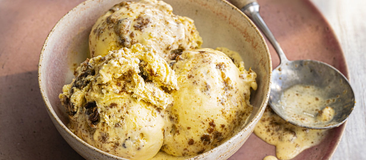 Close-up of a bowl containing 3 scoops of ice cream with a spoon next to it