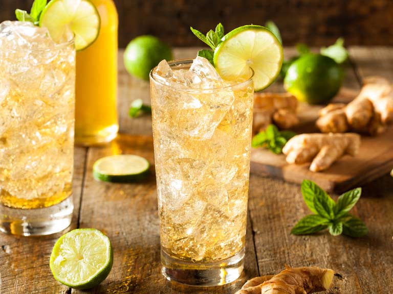 Glasses filled with ice and amber liquid, topped with lime slices and mint