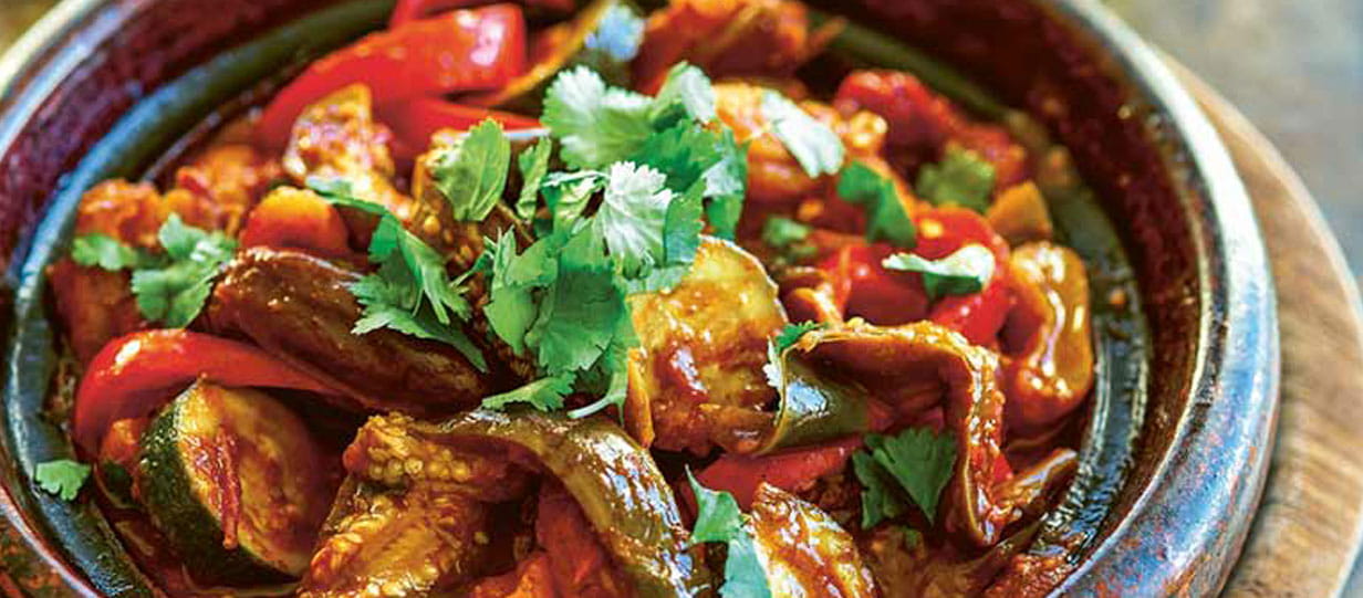 Aubergine and courgette tagine with apricots and dates garnished with a sprig of coriander