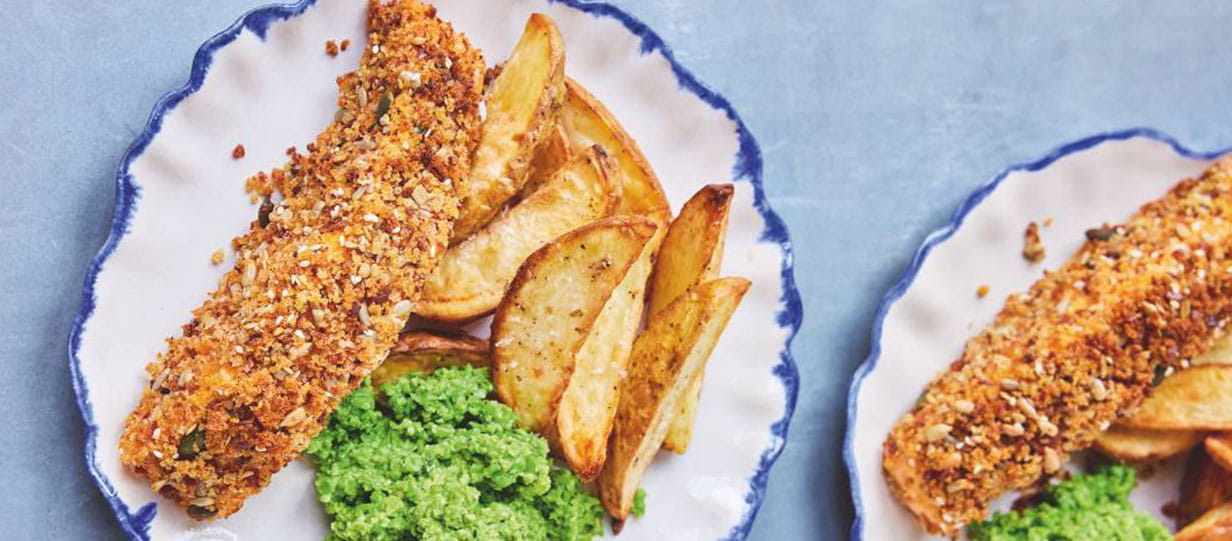 Two plates with crumbed fish, chunky chips and mushy peas