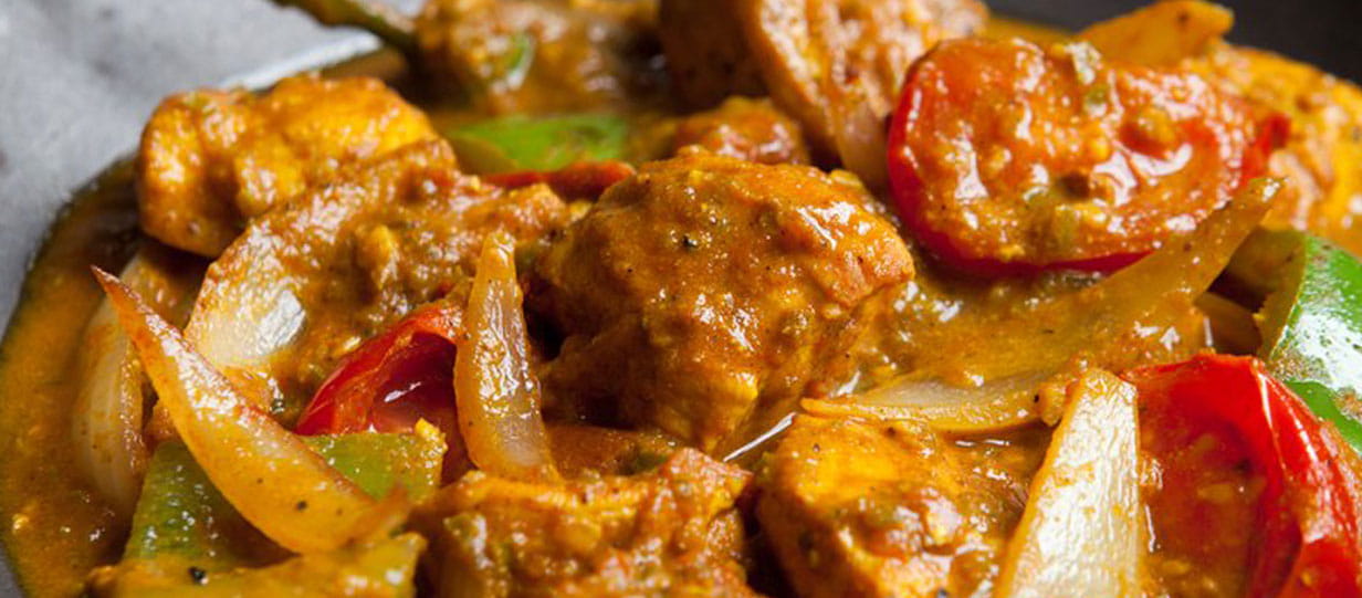 Close-up of a chicken curry with pieces of tomato and chilli