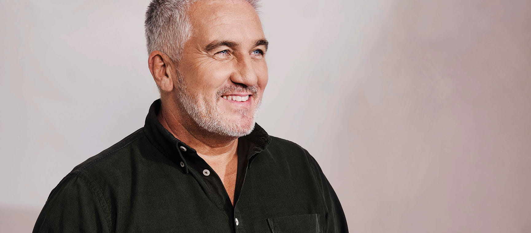 Head and shoulders portrait of Paul Hollywood facing to the right and wearing a black shirt