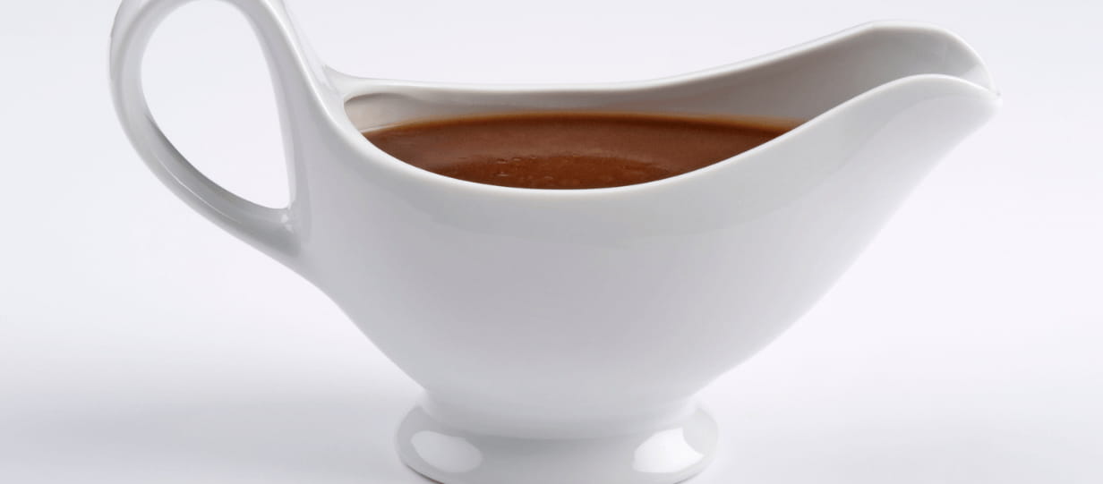 a white gravy boat filled with gravy